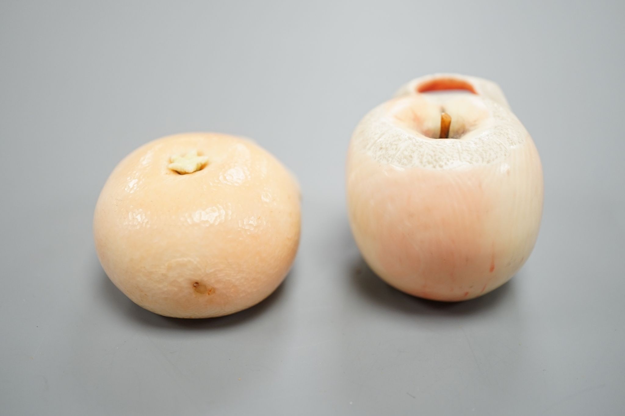 Two Japanese ivory models of a peeled apple and a satsuma, Meiji period, 3.5 cms high.